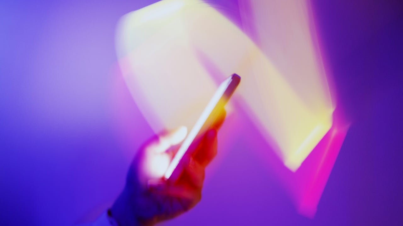 Long exposure Closeup of using smartphone on holographic background - stock photo