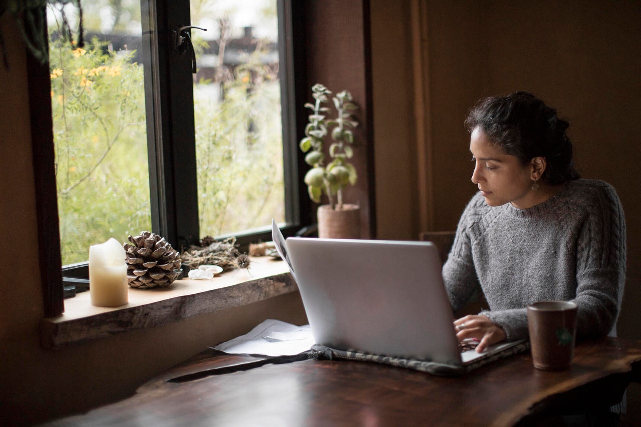 Mulher usando um laptop enquanto trabalha em casa.