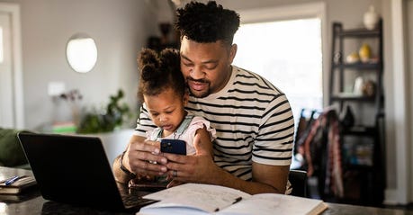 Black Father working from home while holding toddler
