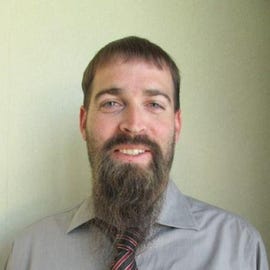 Jonathan Tanner, a white man with short dark-blonde hair and a long beard, smiles in a professional headshot.