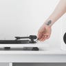 Person touching the needle of a record player with a white bookshelf speaker next to it