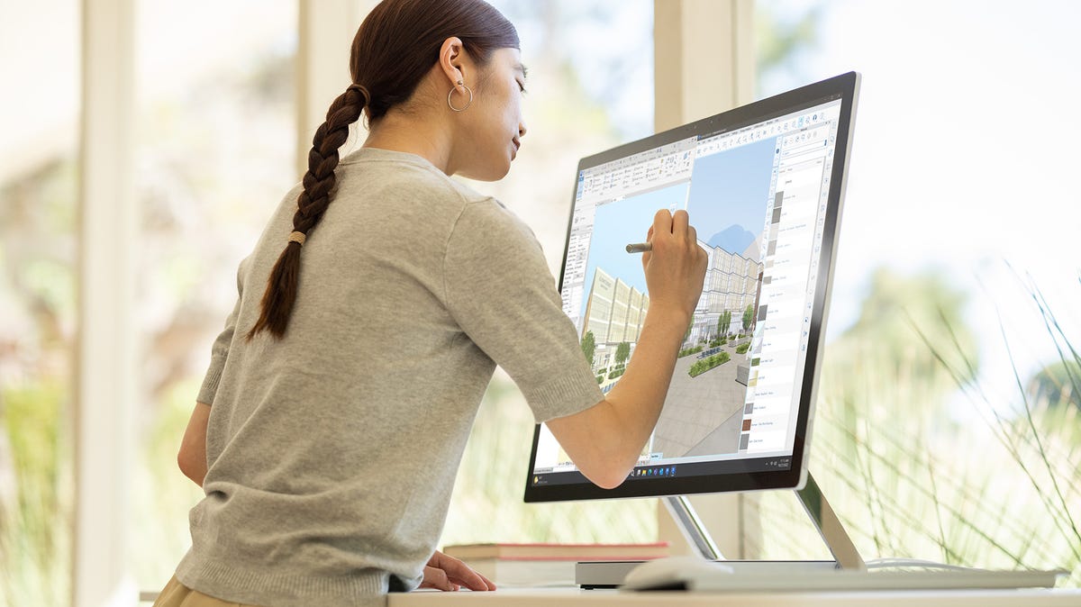 Mulher escrevendo no Surface Studio 2+.