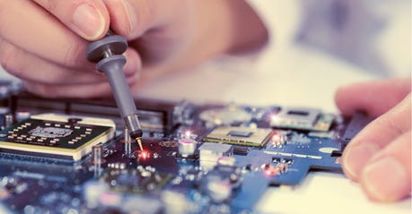 A close-up of hands working on a circuit board.