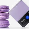 Close-up of a purple Samsung Galaxy Z Flip 4 leaning against a stack of 3 purple macarons