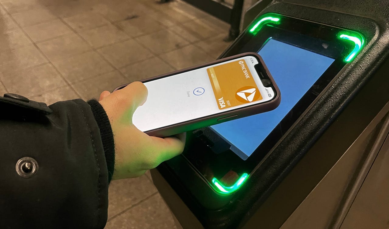 Christina using the Apple Wallet Tap to pay feature on iPhone to enter a subway station.