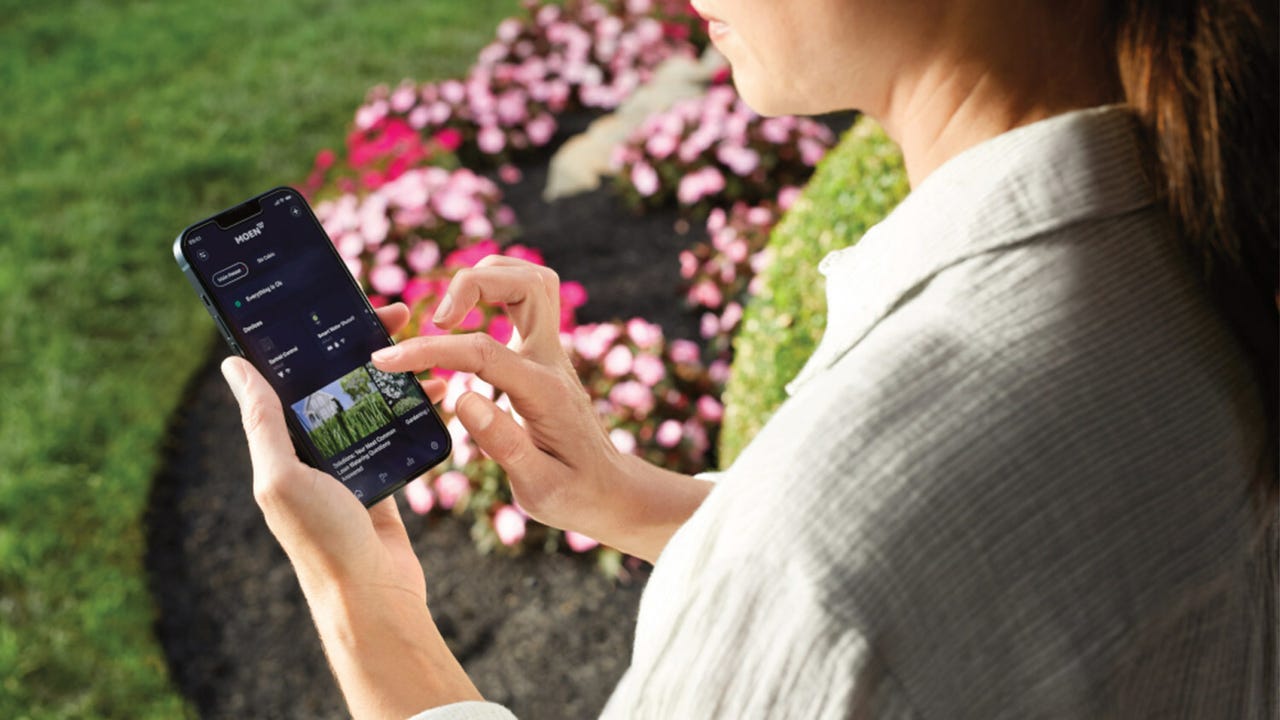 Person in garden holding an iPhone with the open Moen app