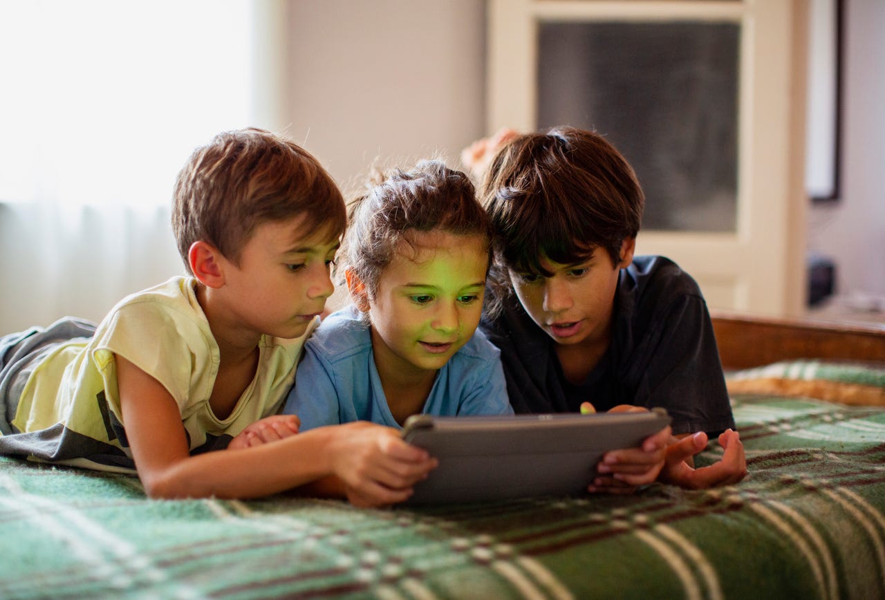 3 young kids watching a video on an iPad