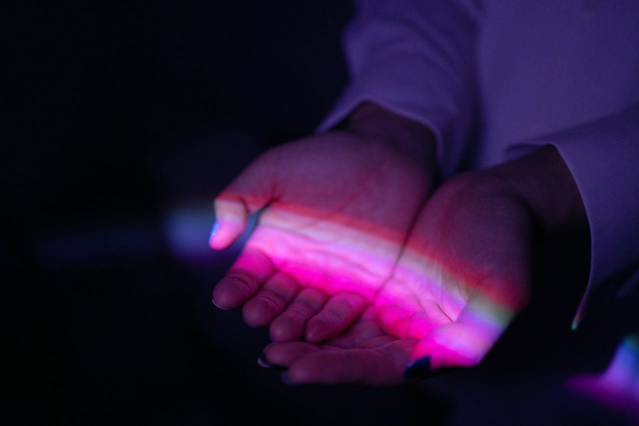 two hands holding a rainbow of light