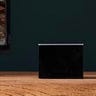 Close up of a black Fire TV cube sitting on a TV stand next to a TV