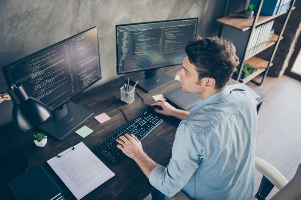 Man working at a desk with two monitors