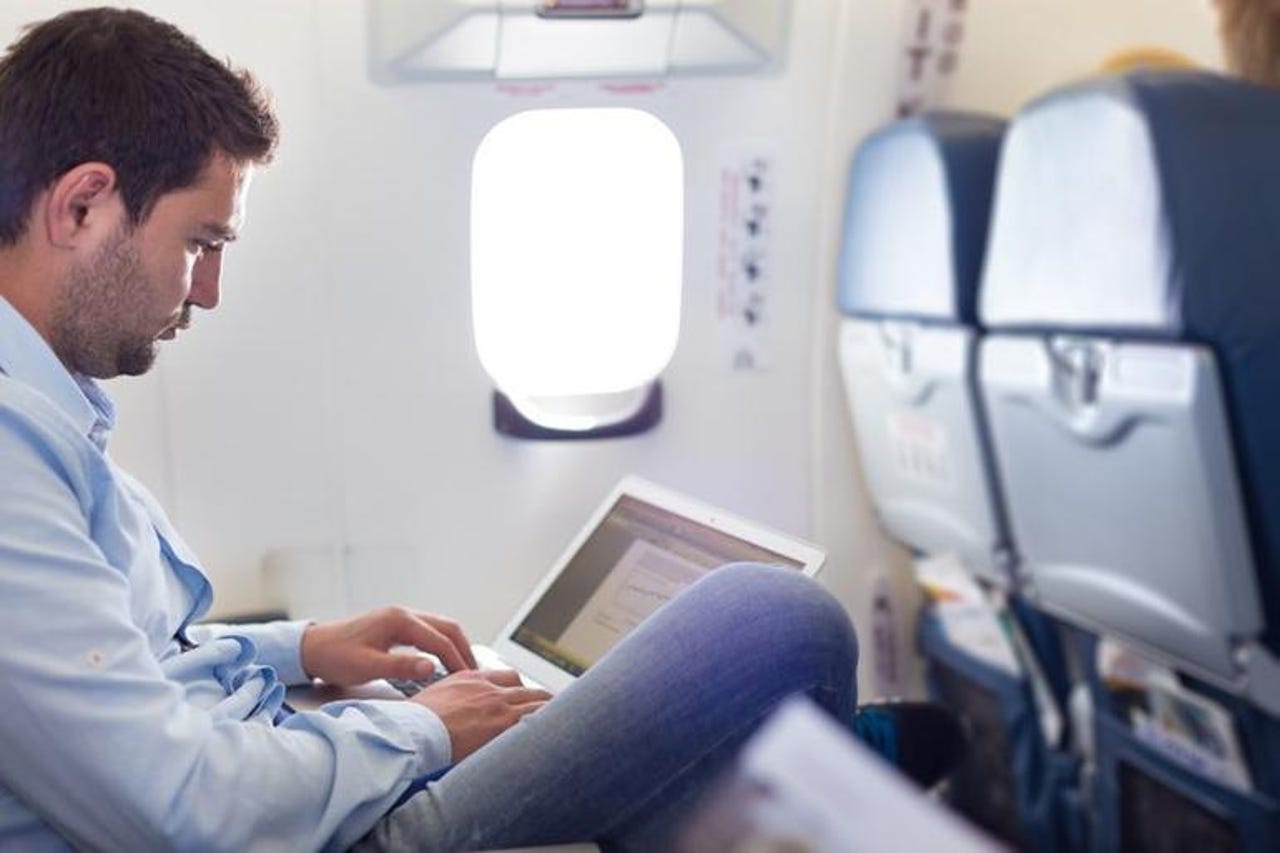 Man working on a laptop on a plane