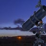 A Celestron AstroMaster telescope against a night sky