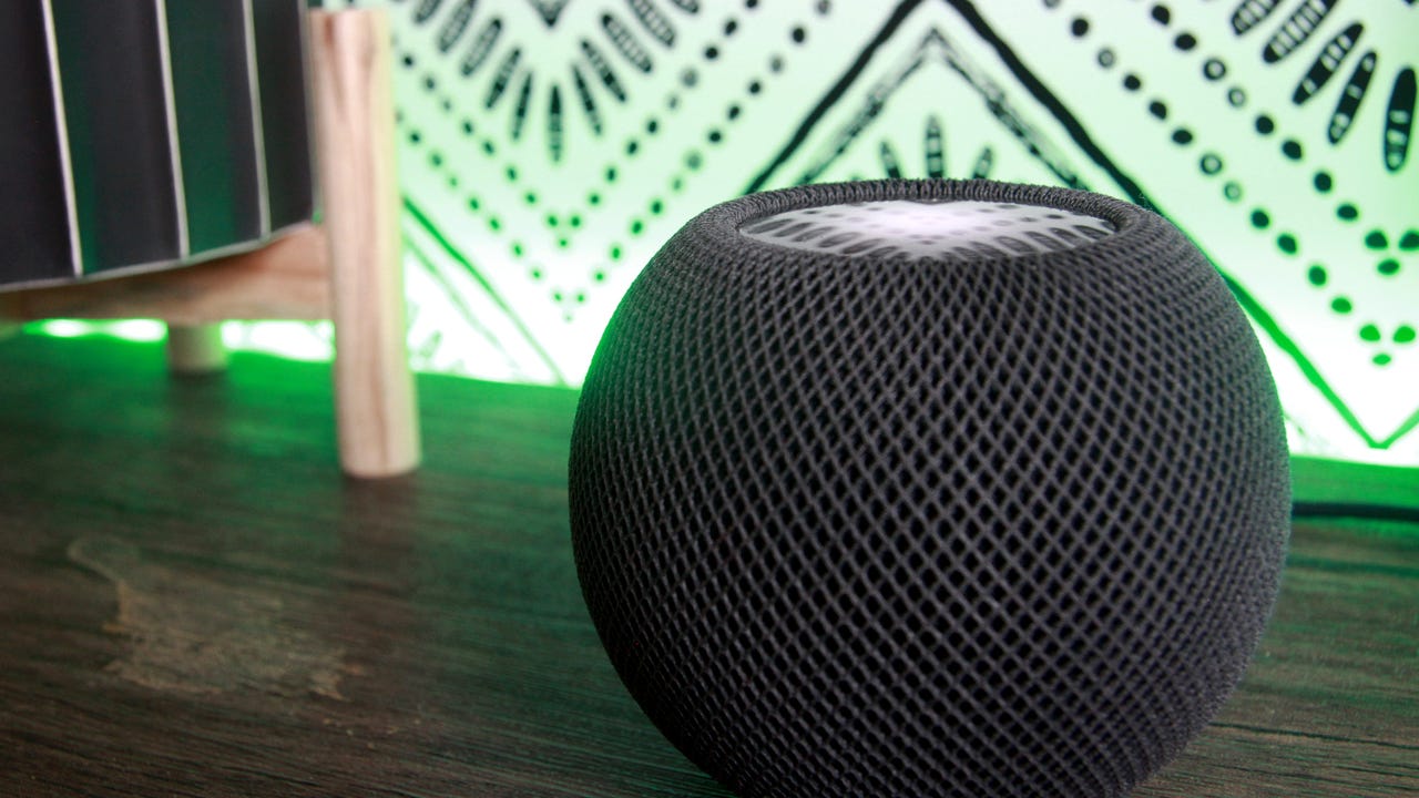 HomePod Mini on table with a green light behind