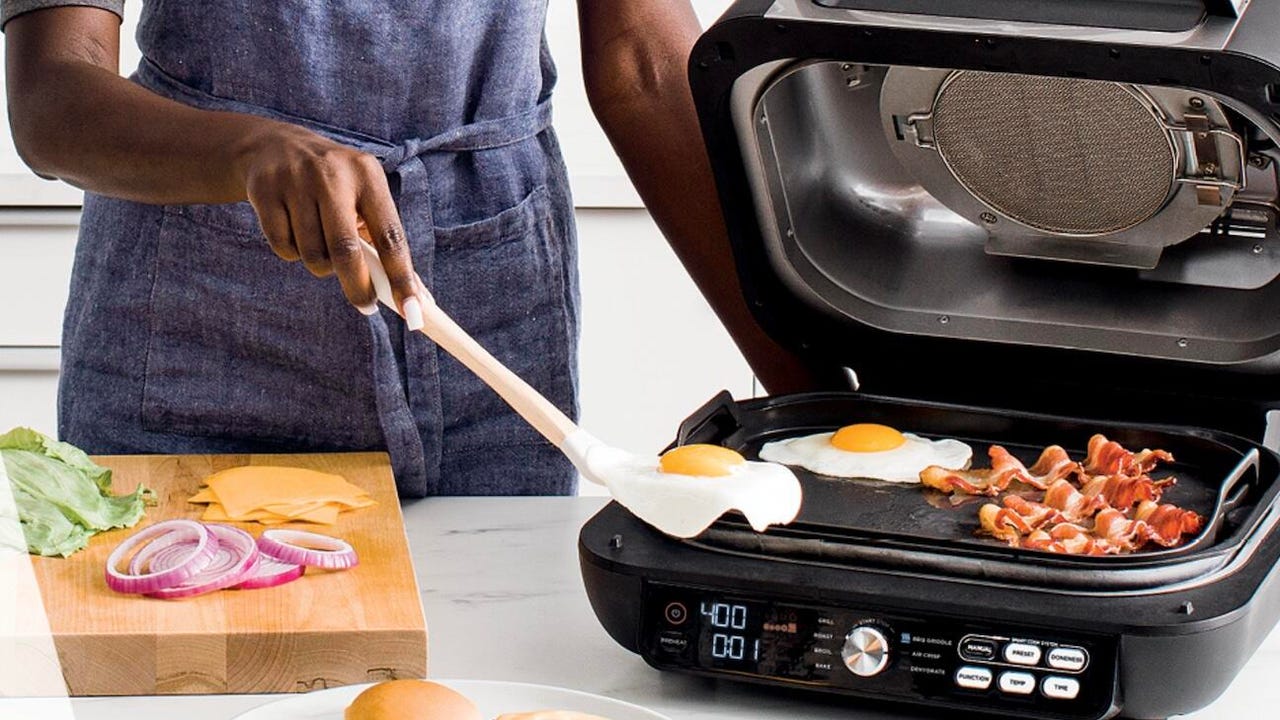 Person cooking eggs and bacon on an indoor grill