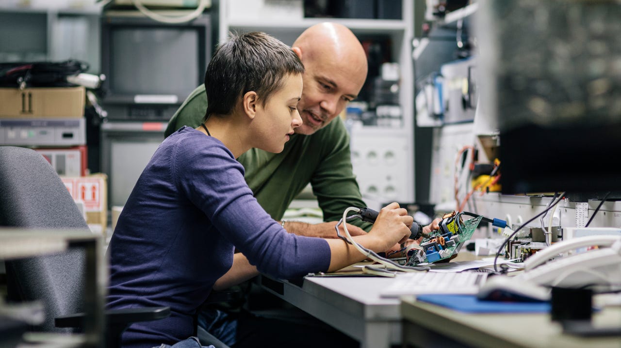 male technician helping a young female electrical engineer