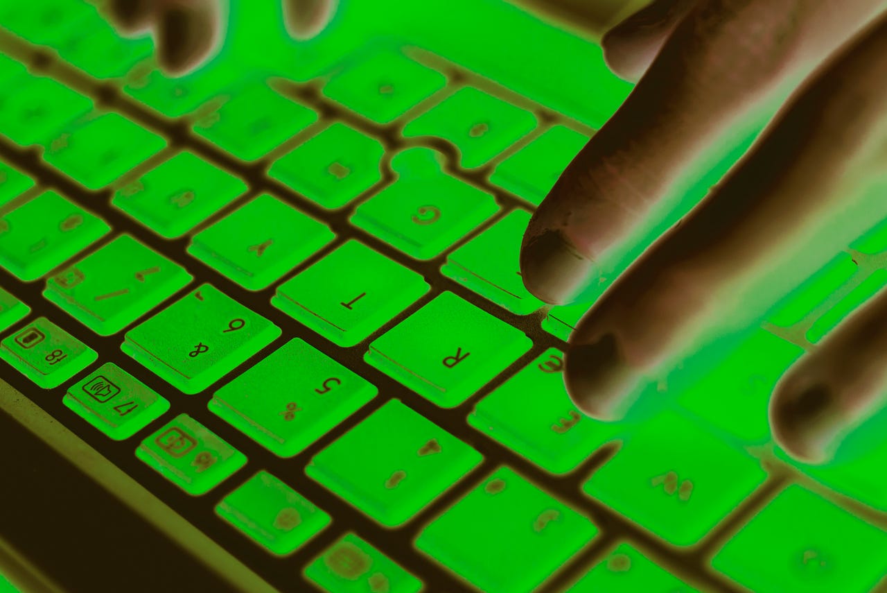 close-up-photograph-of-a-womans-hands-working-with-her-green-lit-laptop