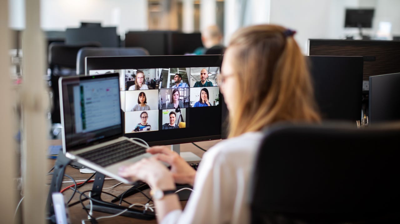 Woman discussing work on video call with team members at office