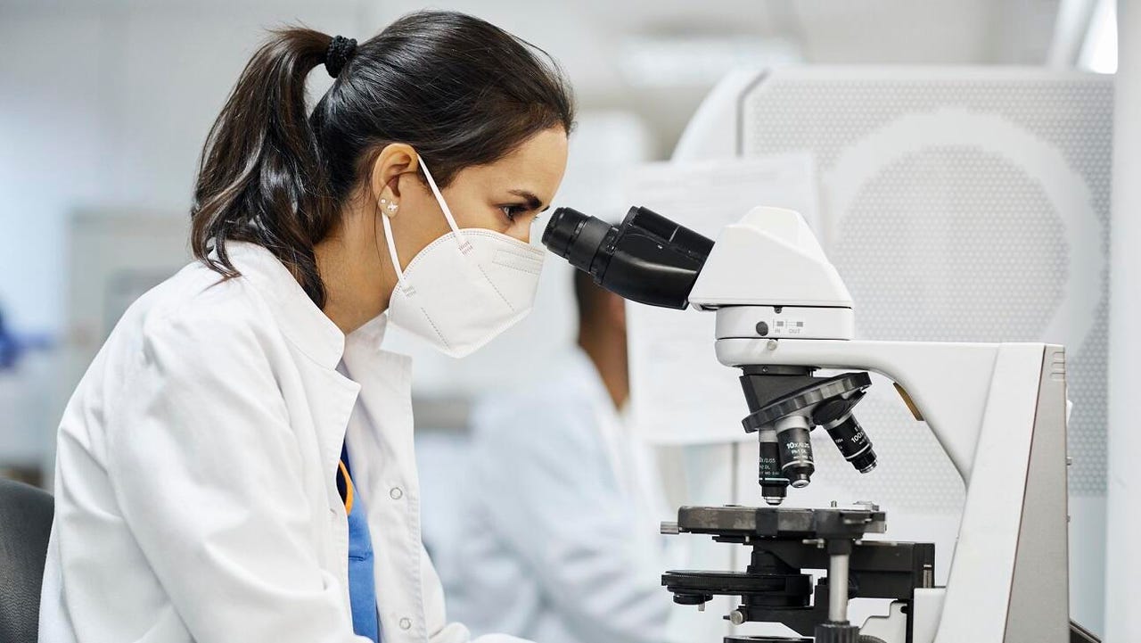 Female scientist using microscope in lab