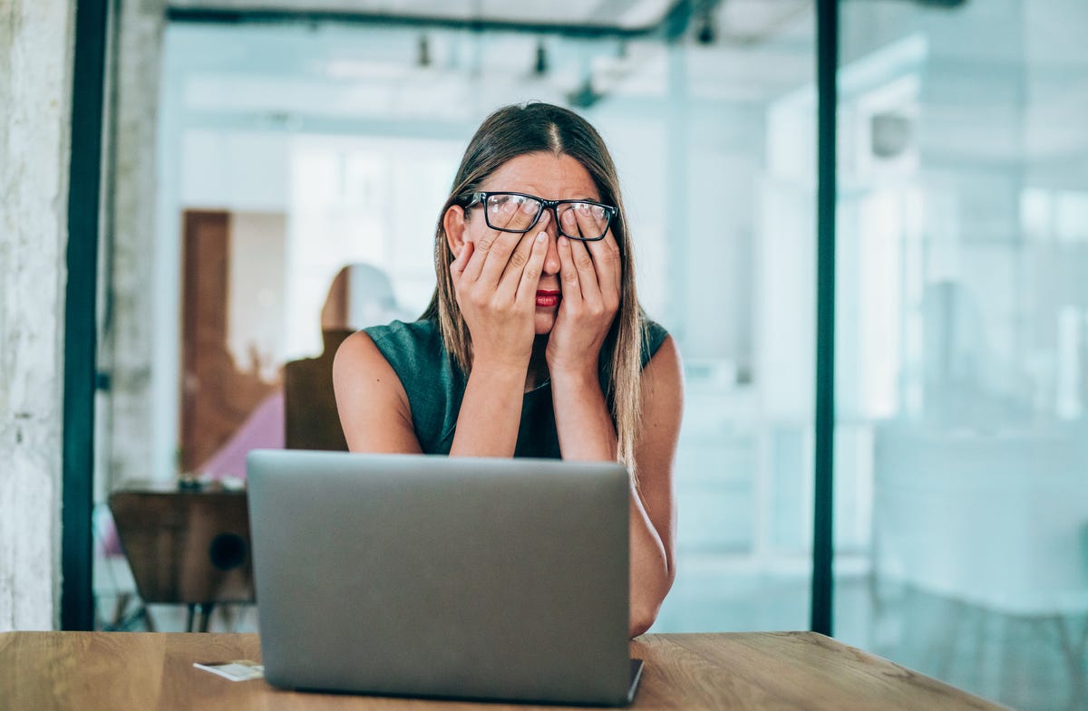 uma-mulher-olhando-estressada-na-frente-de-um-laptop-em-uma-sala-de-reuniões-escritório