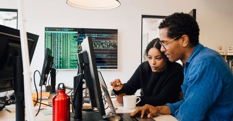 Black man and Black woman tech workers looking at a computer togher