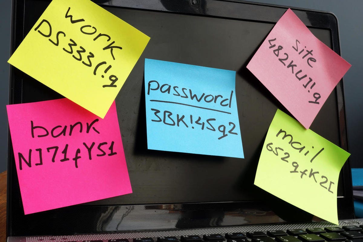 Laptop screen covered with sticky notes of passwords