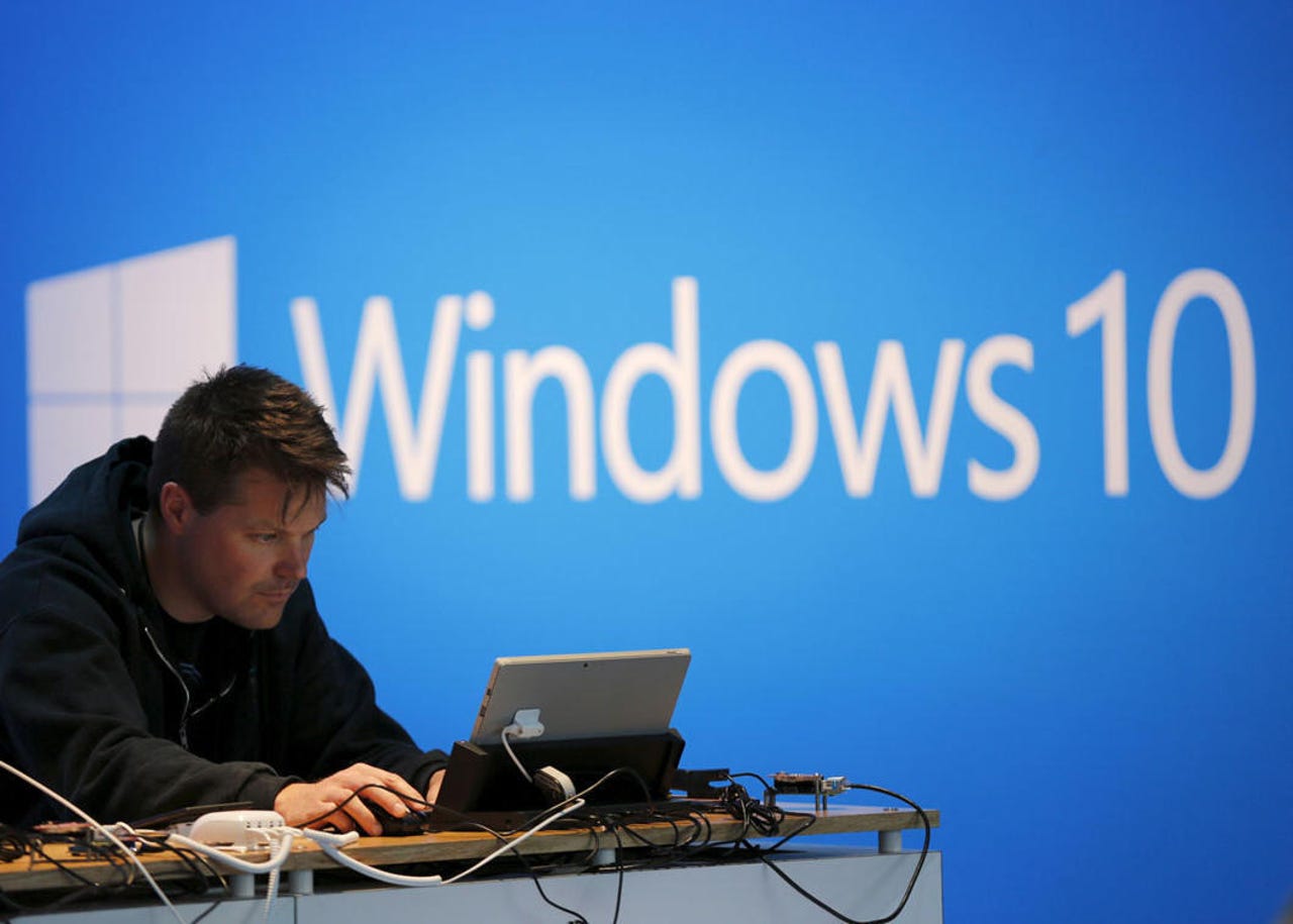 A man works on a laptop computer near a Windows 10 display at Microsoft Build in San Francisco