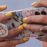 Woman with yellow nails holding a phone with a popsocket attached to the back