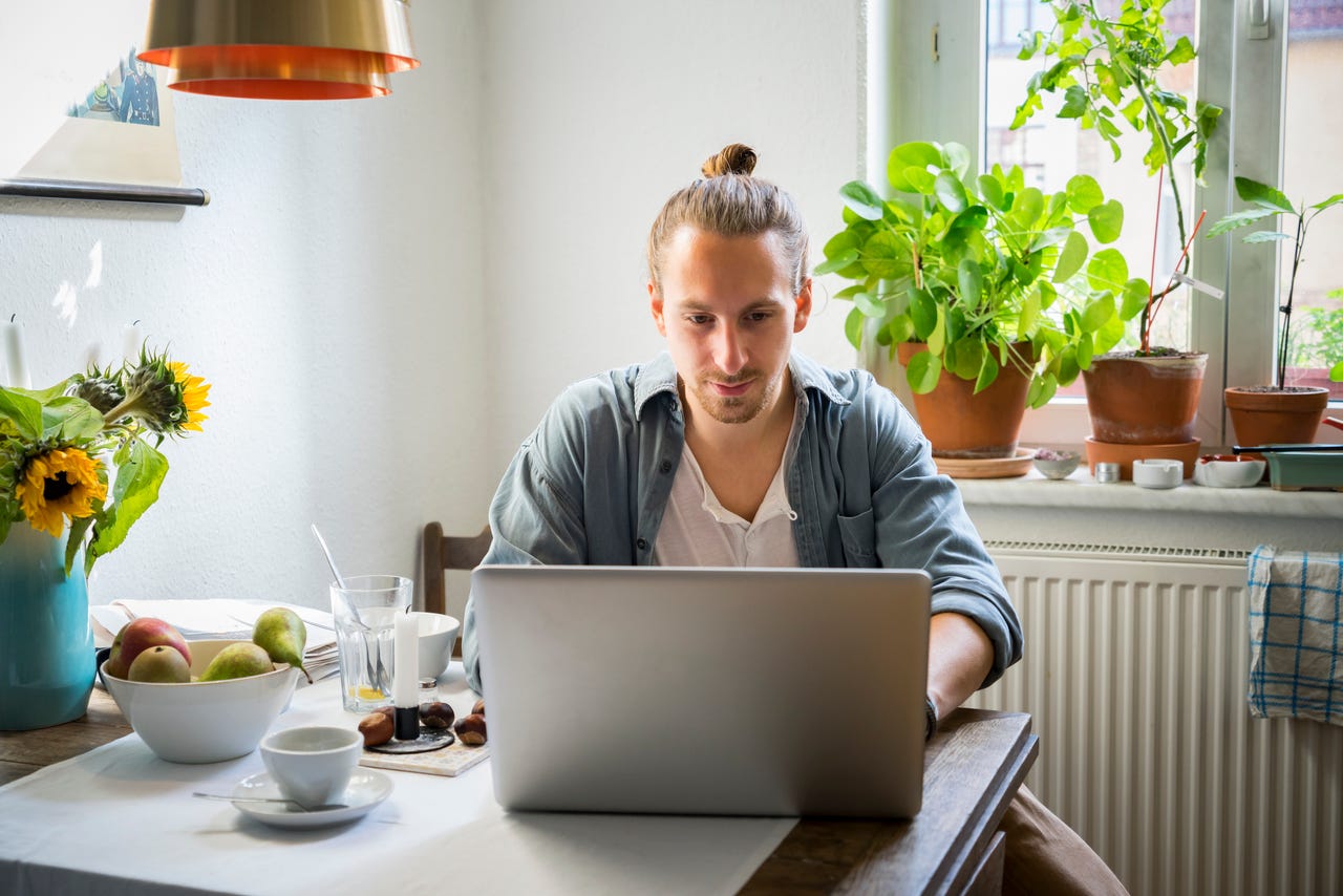 young-man-working-from-home-using-a-laptop-at-his-kitchen-table