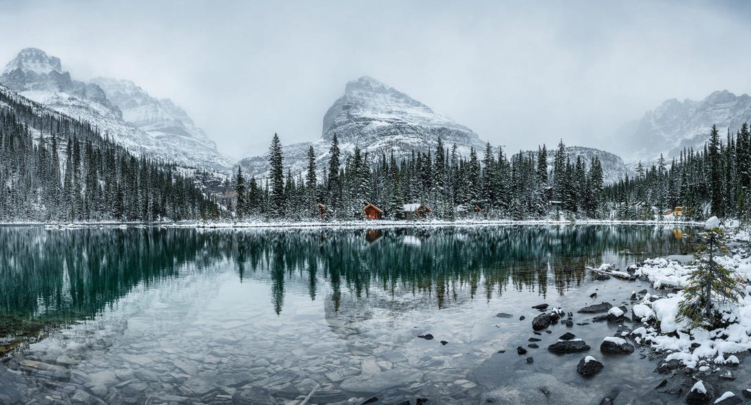 Wooden lodge in pine forest with heavy snow reflection on Lake O'hara at Yoho national park