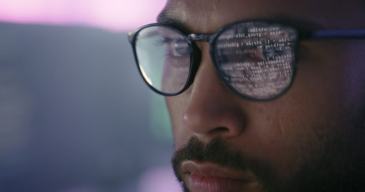 Man with computer code reflected in glasses