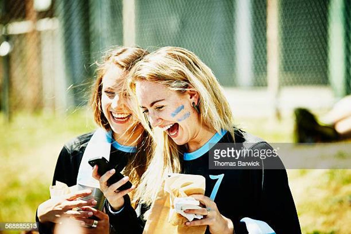 Two athletes laugh over a phone