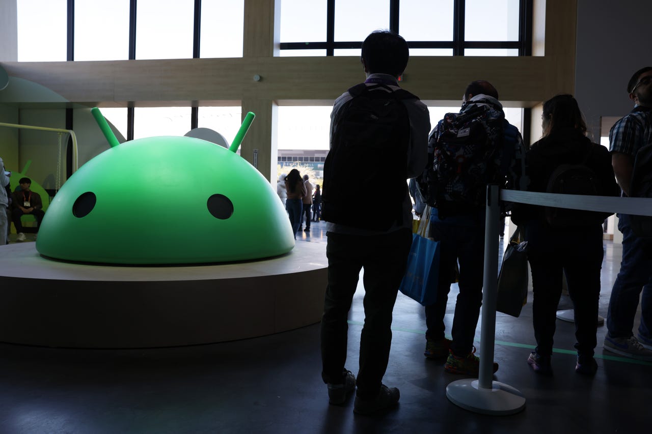 Attendees visit the Google booth where a model of the Android logo is on display