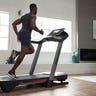 Wide shot of a young Black man using the ProForm Pro 2000 treadmill in his living room