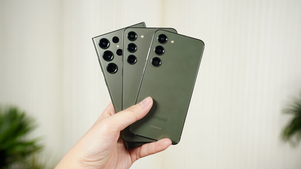 Holding up the Samsung Galaxy S23, S23+, and S23 Ultra in green.