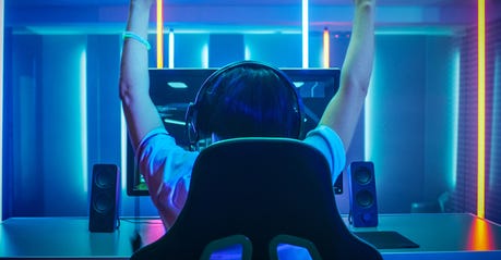 Professional Gamer Playing and Winning in First-Person Shooter Online Video Game on His Personal Computer. Footage Fade out into Bokeh. Room Lit by Neon Lights in Retro Arcade Style. Cyber Sport Championship.