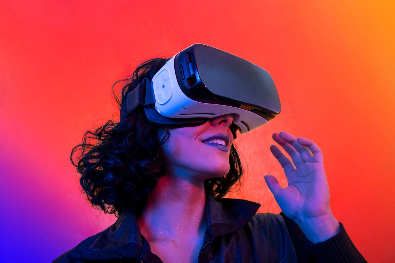 Woman wearing VR headset in front of pink purple gradient background