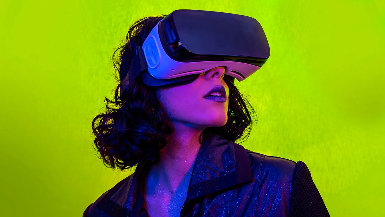 A young woman wearing a VR headset on a bright background with colorful lighting