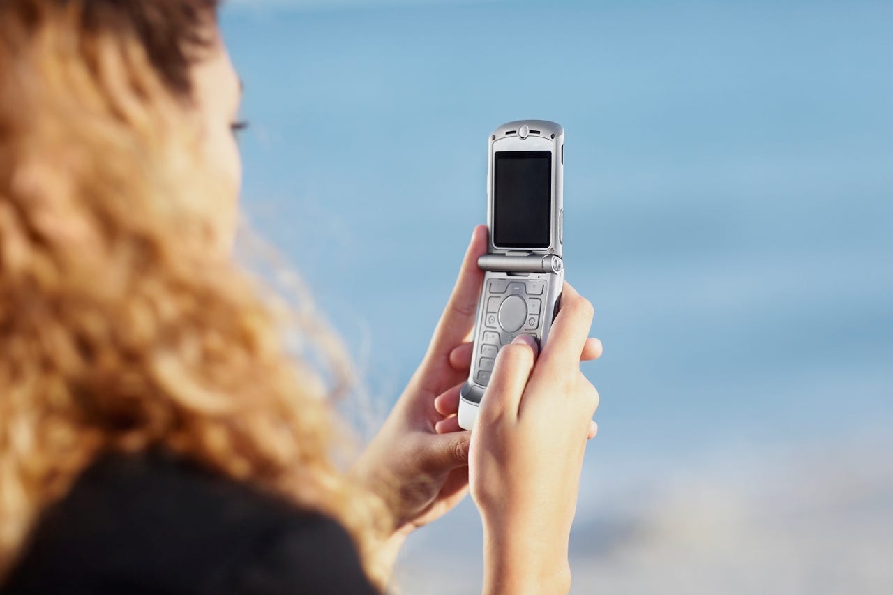 Young woman with blonde, curly hair on a silver flip phone.