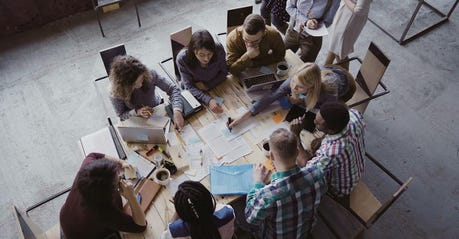 top view of a team of 8 people working at a table in an office