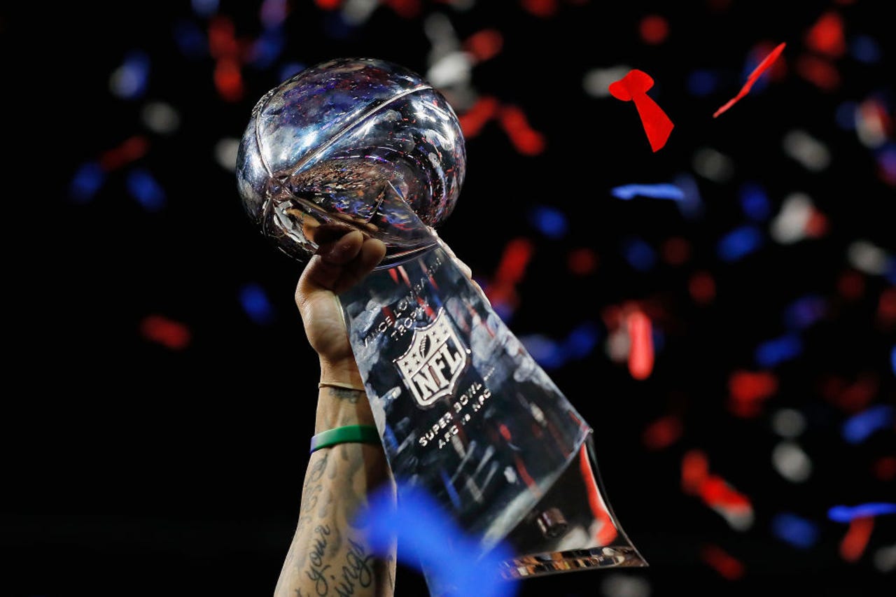 arm holding up Super Bowl trophy amid confetti