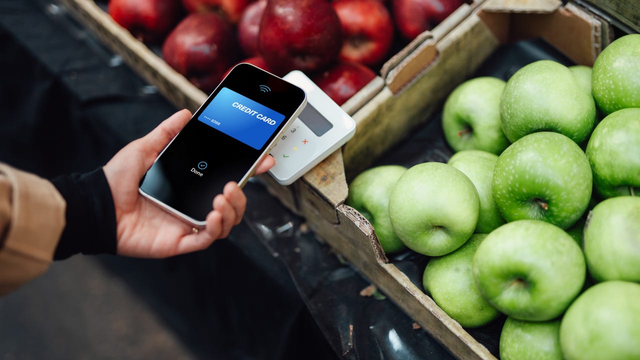 Using a phone to make a contactless payment using Square over bins of apples