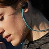 Sweaty woman wearing earbuds with a blue wire coming out of them around her neck