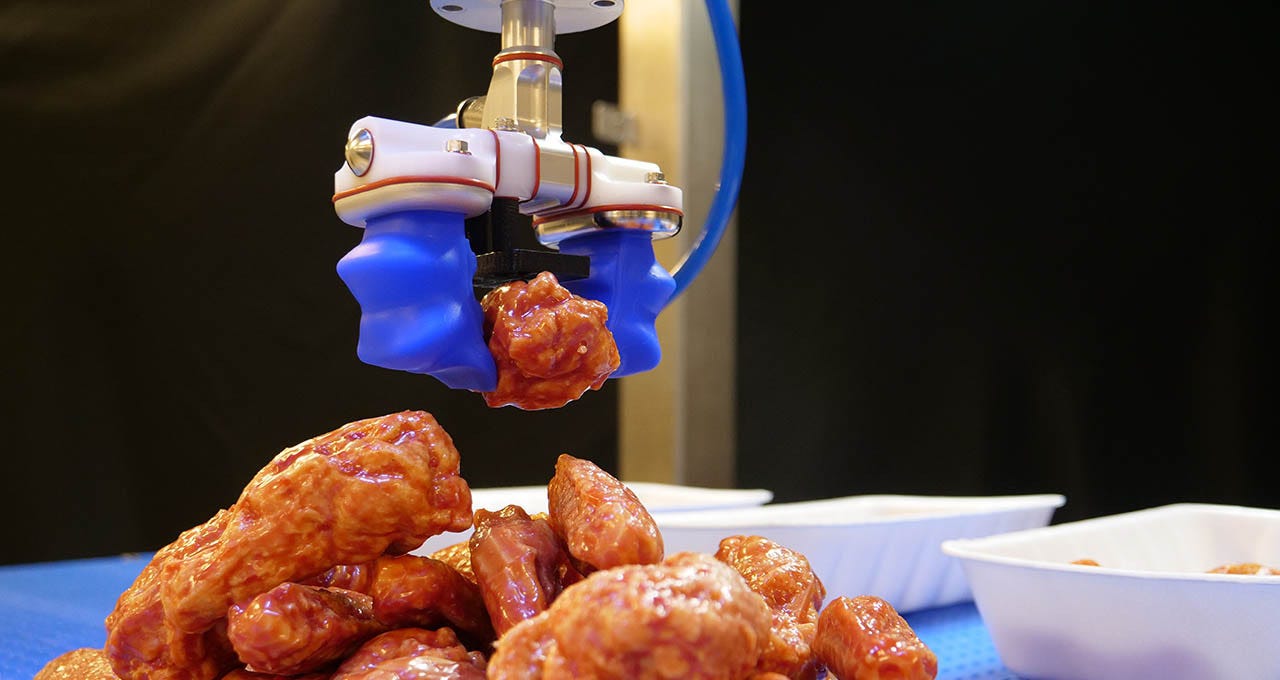 robot arm grips a piece of chicken