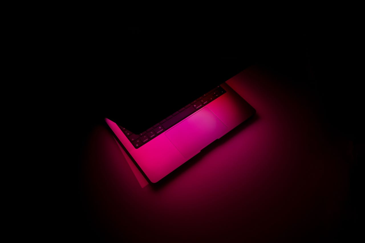 laptop in the dark with pink glow
