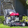 Honda HRN 166cc push mower sitting on a well-manicured lawn in front of a stone house