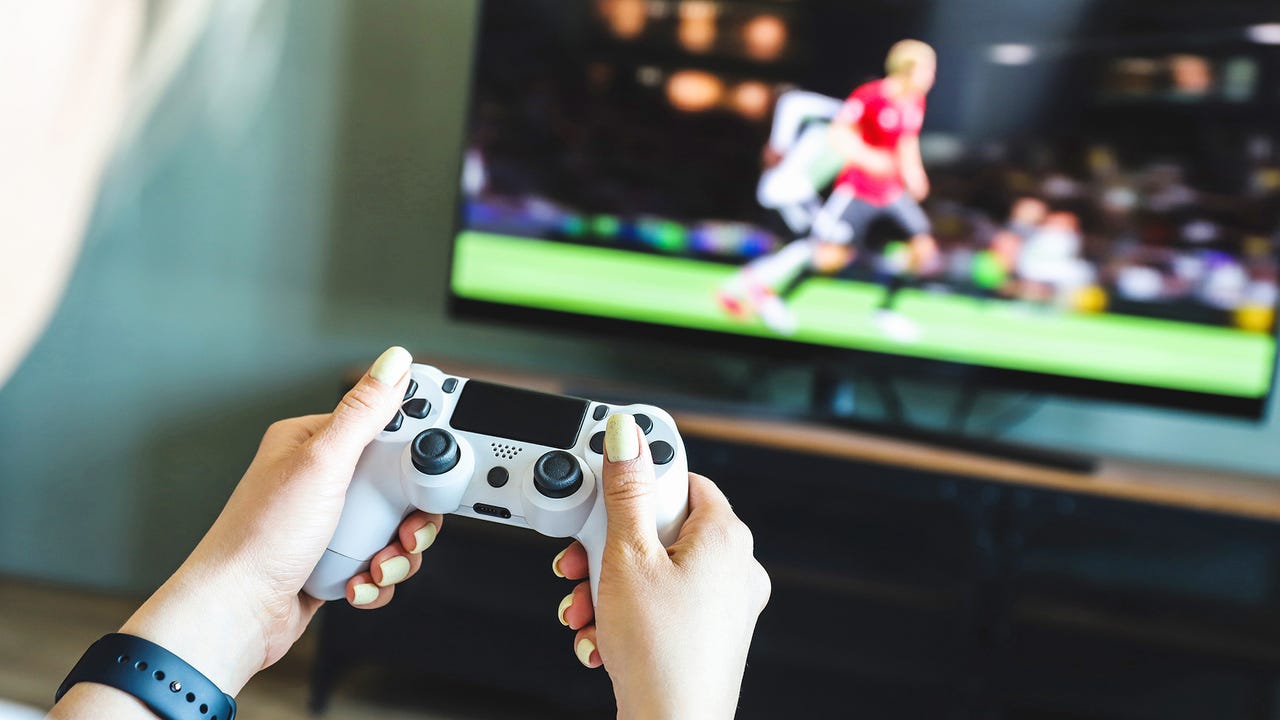 Person playing a video game console. Game is football. Joystick in hands. Selective focus