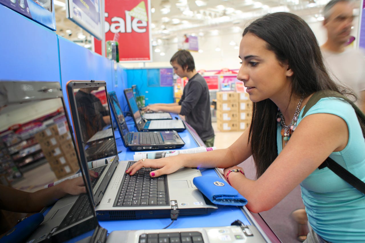 woman trying out one of several laptops on display