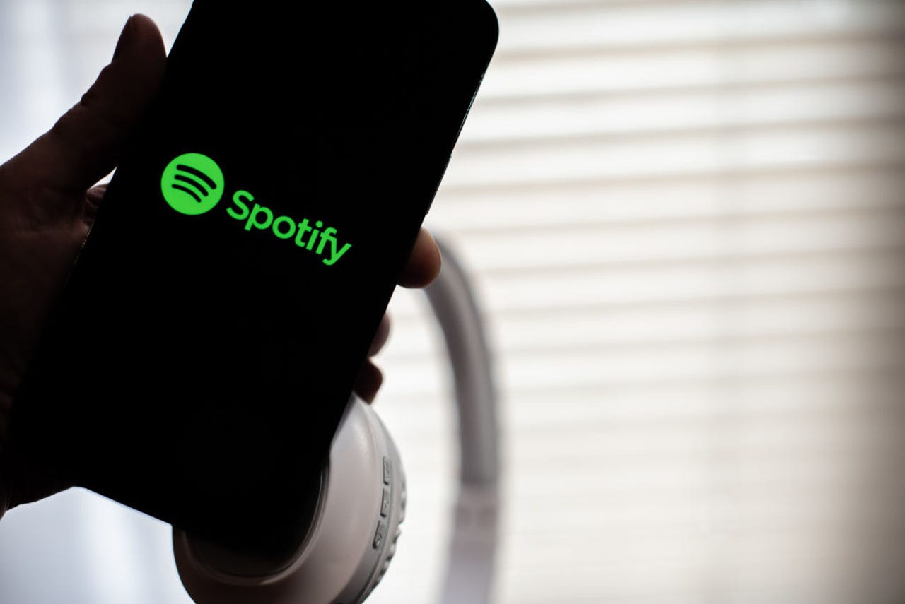 Spotify logo on a phone with headphones behind it