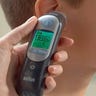 Person holding a smart thermometer up to a child's ear