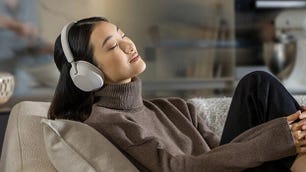Una mujer con auriculares Sony WH-1000XM5 y sentada en un sofá